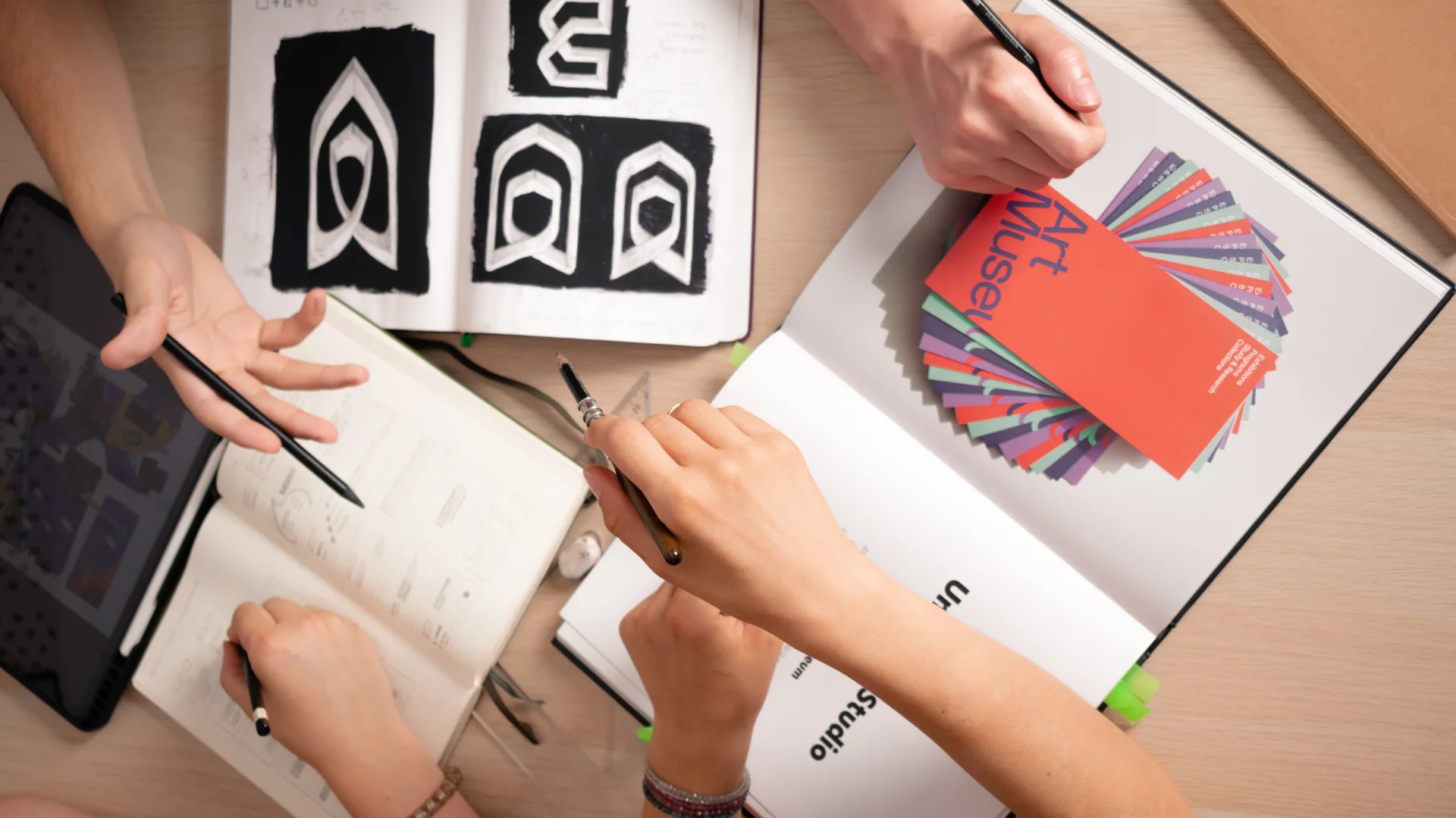 The Embrand team sketching marks in notebooks at the work table