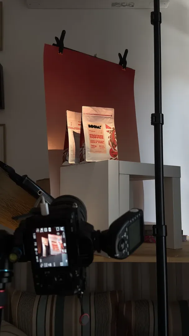 A camera photographing product packs against a red backdrop