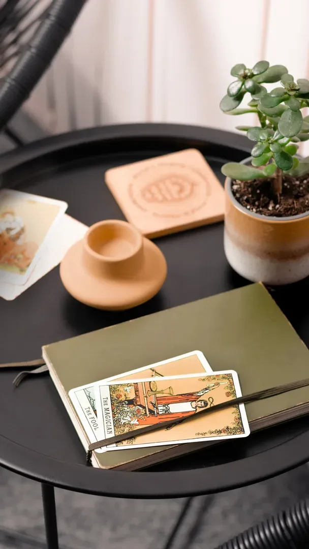 A side table with a notebook, illustrated cards and a potted plant
